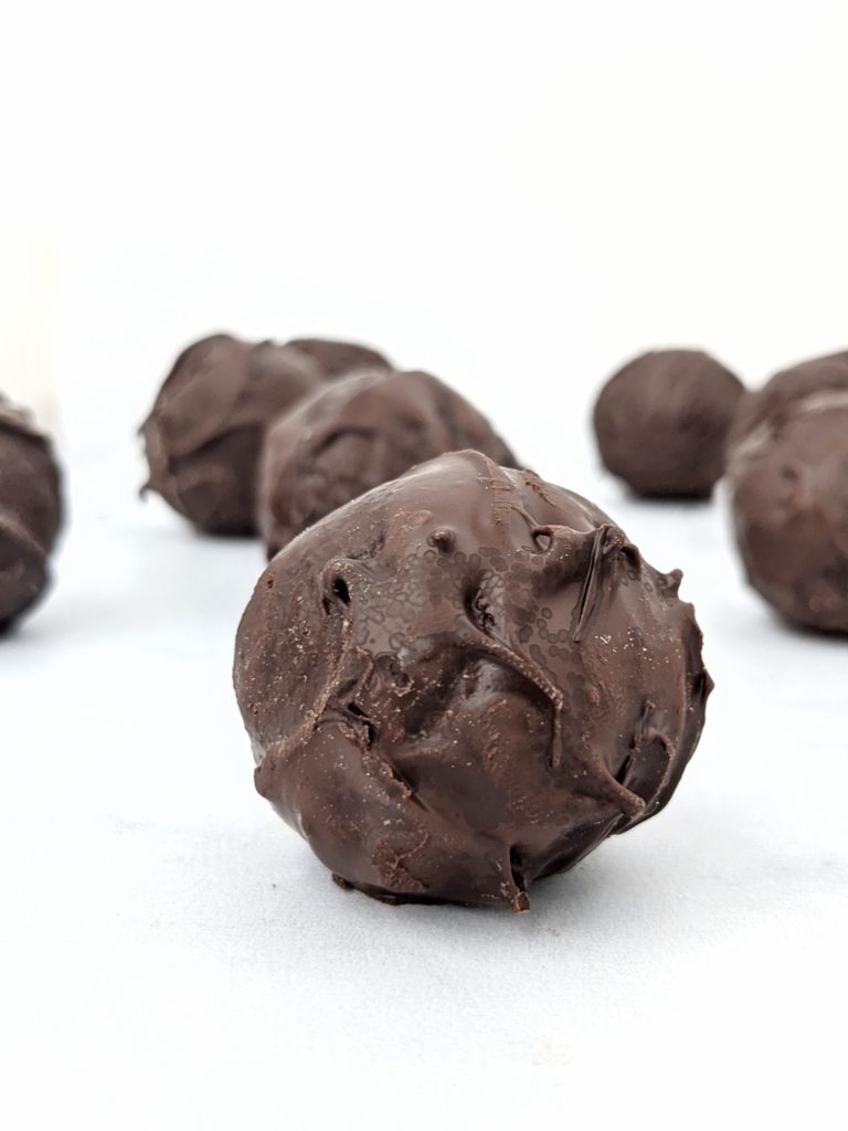 5 Ingredient Chocolate Protein Truffles made with oat flour, cacao powder, protein powder and milk, and dipped in melted chocolate; These no bake protein truffles taste just like brownie balls, and are great for a snack, dessert, or high protein post workout treat!