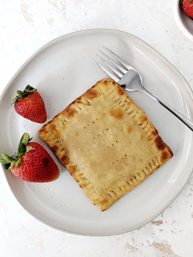 A big single serve Healthy Protein Pop Tarts made with a gluten free base, filled with homemade strawberry jam and topped with high protein sugar free frosting; Vegan too. An easy protein powder poptart made in the air fryer - or baked - to satisfy the sugar cravings.