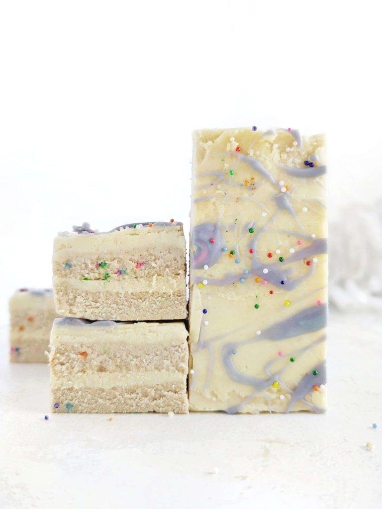 Just superb Birthday Cake Protein Bars recipe complete with no bake protein cake base and protein frosting layers! These funfetti protein bars are low fat, low calorie, sugar free, gluten free and have a Vegan option too. A real celebration cake batter bar!