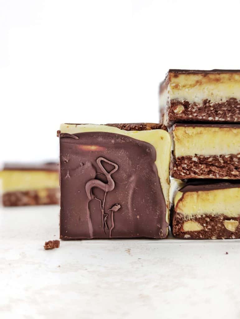 Beautiful Protein Nanaimo Bars with layers of a protein chocolate-coconut, protein powder custard and melted chocolate. These healthy, homemade Nanaimo bars are a perfect low calorie, Vegan, gluten free and sugar free alternative to the popular Canadian treat.