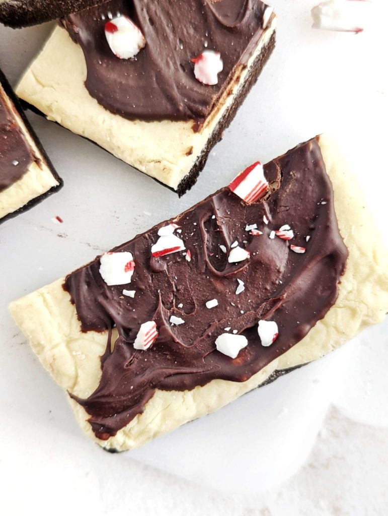 Layered Peppermint Bark Protein Bars with the chocolate peppermint base, thick frosting and chocolate topping - but all sugar free! Healthy, no bake peppermint bars use protein powder instead, as well as oat flour and Greek yogurt.