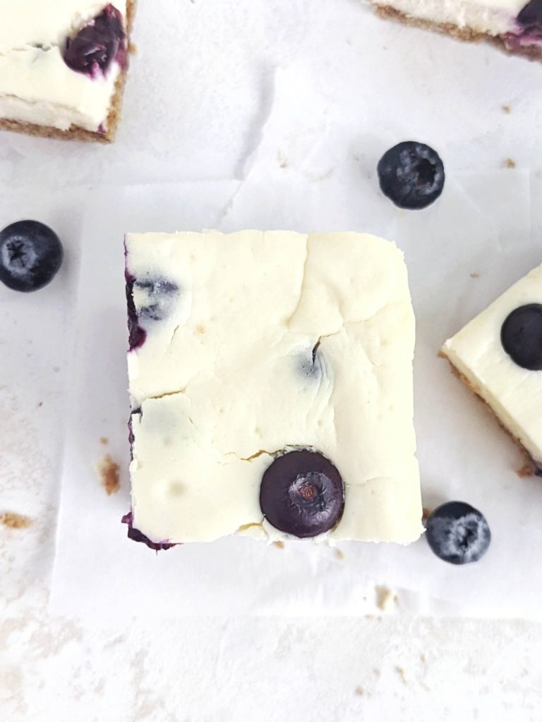 Beautiful and creamy Protein Blueberry Cheesecake Bars aka healthy blueberry cream cheese dessert bites! This healthy blueberry cheesecake bars use protein powder and greek yogurt, and have a healthy cheesecake crust with no butter!