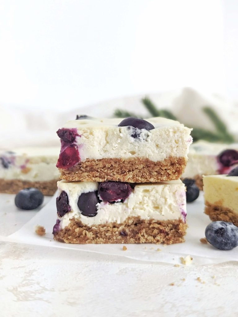 Beautiful and creamy Protein Blueberry Cheesecake Bars aka healthy blueberry cream cheese dessert bites! This healthy blueberry cheesecake bars use protein powder and greek yogurt, and have a healthy cheesecake crust with no butter!