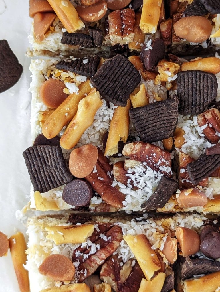 Amazing Protein Magic Bars with 7 layers of sugar free treats including protein shake as condensed milk! These healthy protein magic cookie bars are topped with sugar free chocolate chips, coconut, pecans, pretzels and chocolate cereal too. No condensed milk and a keto option too!