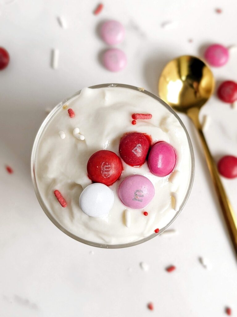 Perfect Valentine’s Day Protein Dessert jars with layers of a protein cookie, protein pudding and Valentines M&Ms. A healthy Valentine’s Day trifle for two made in 5 minutes!