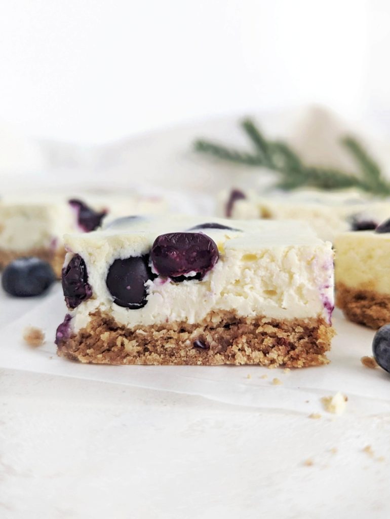 Beautiful and creamy Protein Blueberry Cheesecake Bars aka healthy blueberry cream cheese dessert bites! This healthy blueberry cheesecake bars use protein powder and greek yogurt, and have a healthy cheesecake crust with no butter!